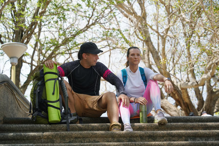 A man and a woman are comfortably seated on a set of stairs after hikingの写真素材