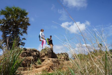 A young couple are hiking on a rugged rocky cliff that offers a view of the oceanの写真素材
