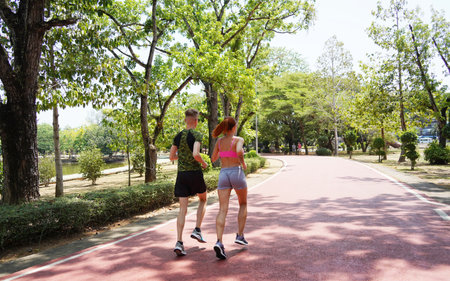 A man and a woman are jogging together in a beautiful parkの写真素材