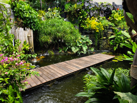 A charming wooden bridge spans a tranquil pond in a serene gardenの写真素材