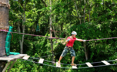 A man is walking across a challenging ropes course in the extreme parkの写真素材