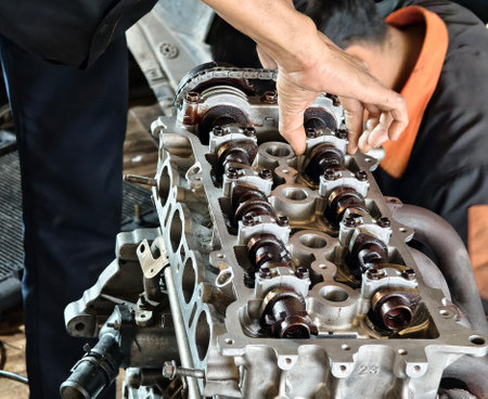Two men are diligently working on a car engine inside a garageの写真素材