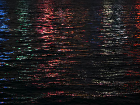 The colorful city lights create beautiful reflections in the water at nightの写真素材