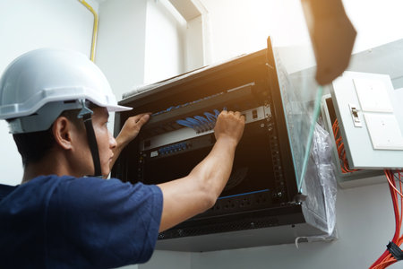A maintenance technician works in a server room with a fiber optic hubの写真素材