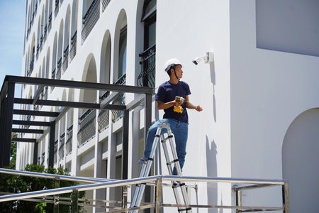 A technician installs a CCTV camera on the facade of a residential buildingの写真素材