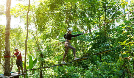 A man and a woman is walking across a challenging ropes course in the extreme park