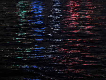 The colorful city lights create beautiful reflections in the water at nightの写真素材