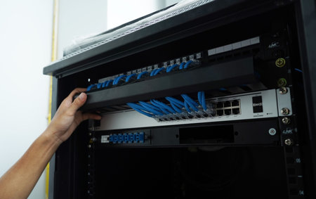 A maintenance technician works in a server room with a fiber optic hub