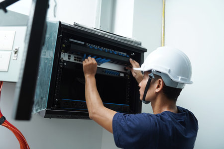 A maintenance technician works in a server room with a fiber optic hub
