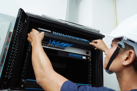 A maintenance technician works in a server room with a fiber optic hub