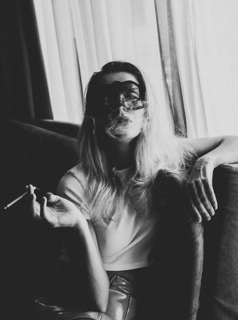 Young woman with black mask posing on the sofa