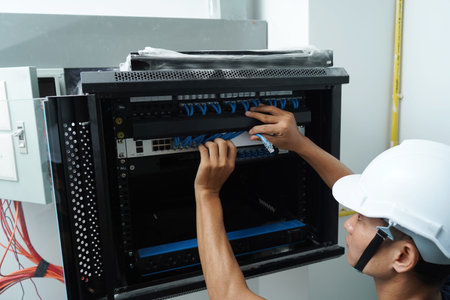A maintenance technician works in a server room with a fiber optic hub