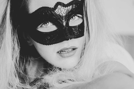 Sexy nude young woman with black mask posing in the bedroom