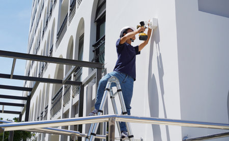 A technician installs a CCTV camera on the facade of a residential buildingの写真素材