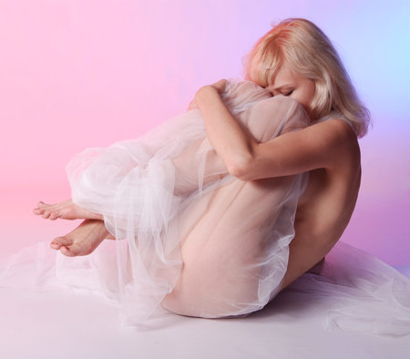 Nude woman posing on rose background in studioの写真素材