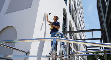 A technician installs a CCTV camera on the facade of a residential building