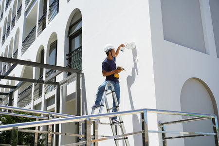 A technician installs a CCTV camera on the facade of a residential buildingの写真素材