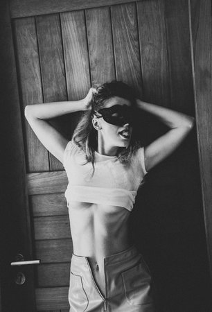 Young woman with black mask posing near the doorsの写真素材