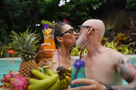 A man and a woman are having fun and drinking cocktails in the pool.の写真素材