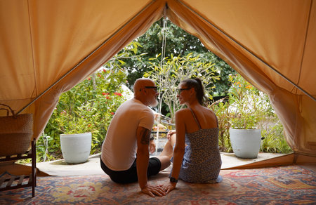 A man and a woman are comfortably sitting together inside of a tentの写真素材