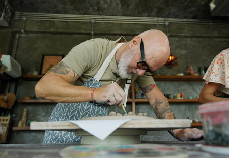 An adult man makes a ceramic plate in a workshop