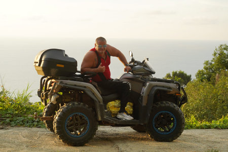 A man engages in extreme ATV riding on mountains in the evening