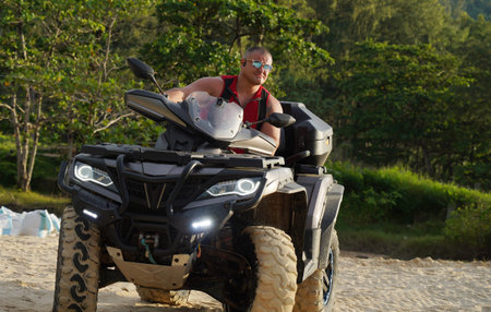 A man engages in extreme ATV riding on sand beach early in the morning