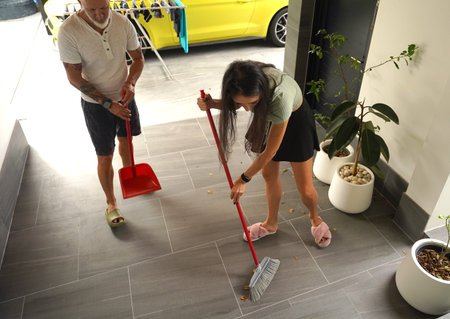 Man and woman enjoy lighthearted cleaning session on their porch during summer