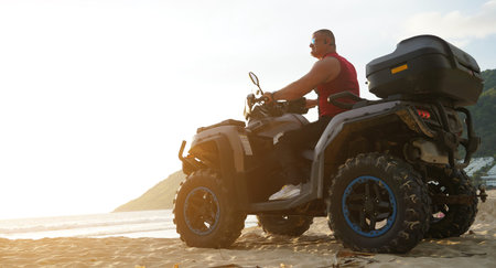 A man engages in extreme ATV riding on sand beach early in the morning