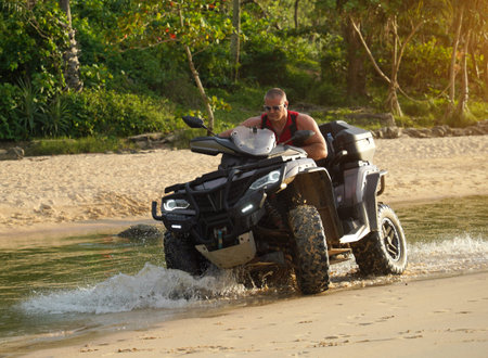 A man engages in extreme ATV riding on sand beach early in the morningの写真素材
