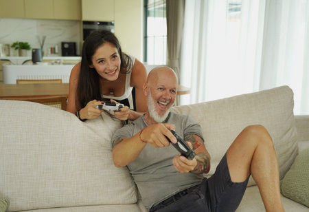 Two adults video gaming on sofa in friendly competitive