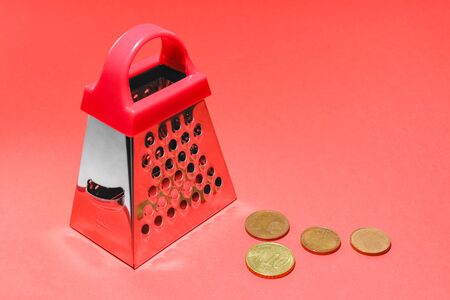 kitchen grater on a red background with Euro coinsの写真素材