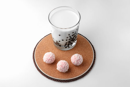 pink chocolate candy and a glass of milk on a white background. candy ball macro. isolate. High...