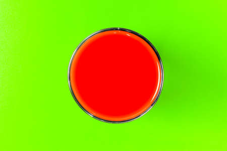 a glass of tomato juice on a green background. hard shadow. the view from the top. isolate. High quality photoの写真素材