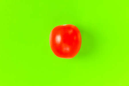 red tomato on a green background. hard shadow. isolate. High quality photoの写真素材