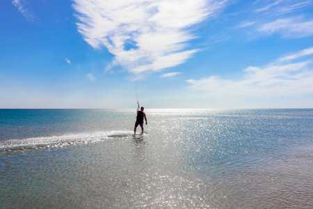 a kitesurfer surfing on the smooth azure water. recreational sport. A Man Rides A Kiteboarding In...