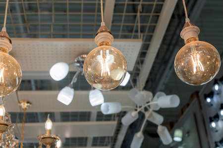 classic retro style vintage incandescent lamp on the ceiling against the background of other lampsの写真素材