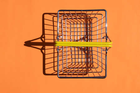 steel supermarket basket with hard shadow on colored backgroundの写真素材