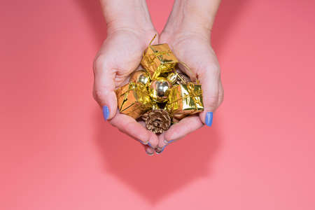 christmas toy in womens hands on a pink backgroundの写真素材