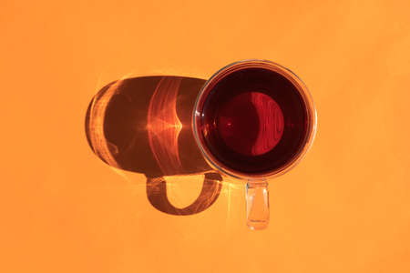 a mug of tea with a hard shadow on an orange backgroundの写真素材
