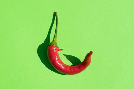 red hot pepper on a green background with a hard shadowの写真素材