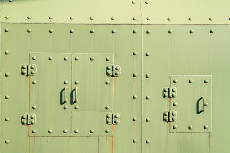 Rusty green metal surface with rivets and secured panels in bright sunlightの写真素材