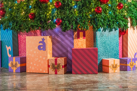 Colorful Christmas presents arranged beneath a festive tree in a cozy settingの写真素材