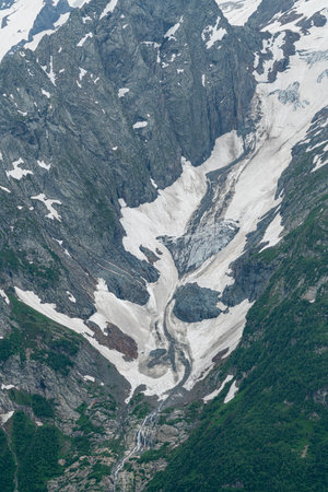 Mountain Glacier Retreat Reveals Rocky Terrain and Lush Greenery in Summerの写真素材