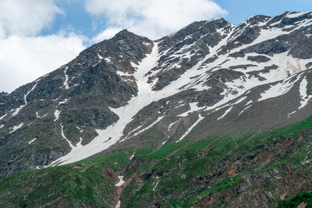 Snowy Mountain Landscape With Lush Greenery Under a Blue Skyの写真素材