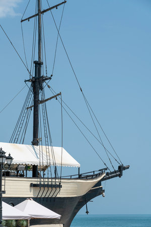 Historic Sailing Ship Docked by the Coastline Under Clear Blue Skiesの写真素材