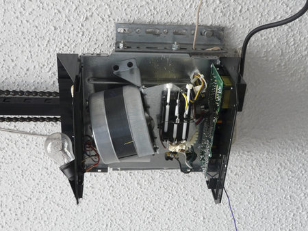 Close-up of an automatic garage door opener motor gear drive needing repair at a residence.