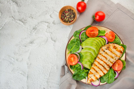 Grilled chicken breast and fresh vegetable salad with spinach leaves, avocado and tomatoes on a light background. Salad of greens with meat. The concept of diet food. copyspace. food banner.の写真素材