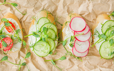 Various vegetarian sandwiches with vegetables and herbs on parchment on a light table. Proper nutrition. diet food. food background. view from above. close-up.の写真素材