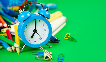 back to school. Alarm clock and school equipment on a green background. copyspace.の写真素材